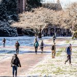 Students walking through The Quad in winter with light snow on the ground